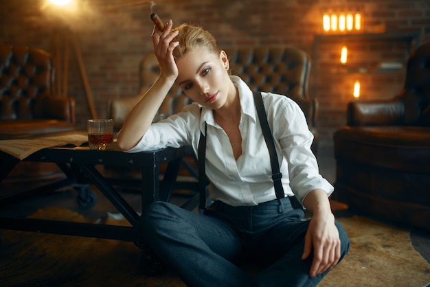 Femme assise sur le sol avec du whisky et du cigare