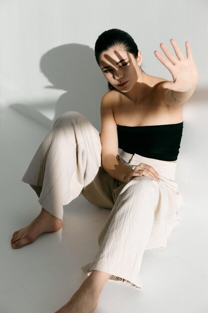 Femme assise sur le sol à l'intérieur vêtements à la mode lumière brillante photo de haute qualité