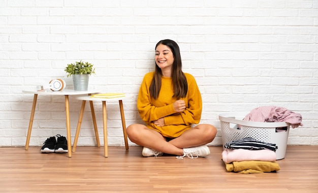 Femme assise sur le sol avec un panier de vêtements