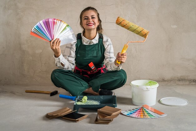 Femme assise sur le sol et posant avec des outils de peinture