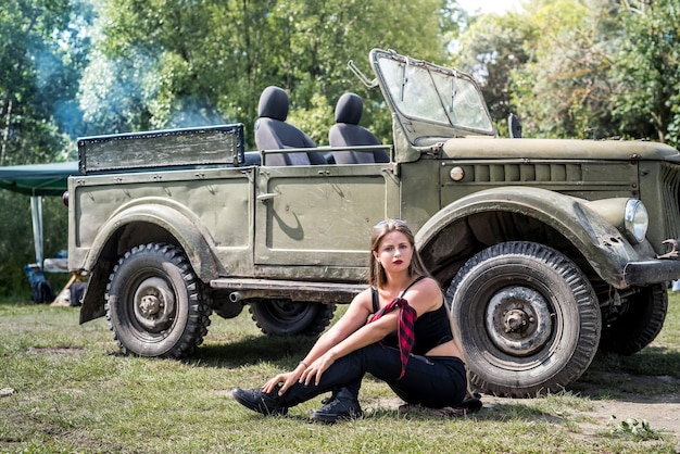 Femme assise sur le sol près de la voiture militaire