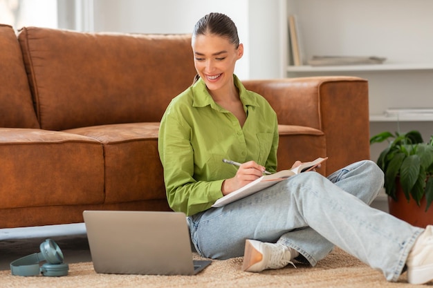 Une femme assise sur le sol travaillant sur un ordinateur portable