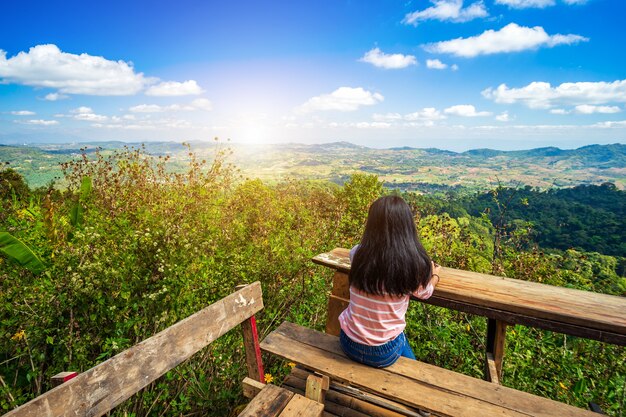 femme assise à la table ou banc de bois en admirant la montagne