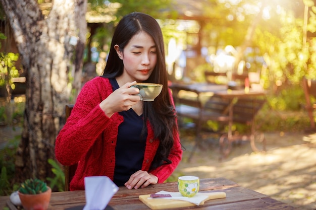 femme assise sur une table et boire une tasse de café dans le jardin