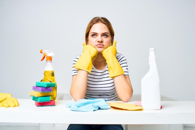 Femme assise à la table des gants en caoutchouc nettoyage service de détergent de travaux ménagers