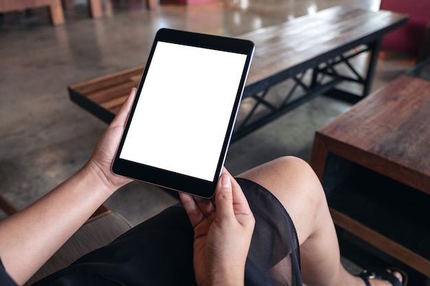 Femme assise et tenant un tablet pc noir avec écran de bureau blanc vierge