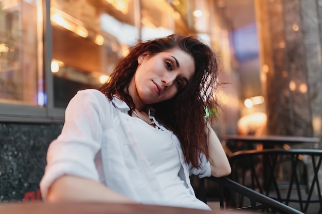 Femme assise sur la terrasse le soir d'été. Photo de haute qualité