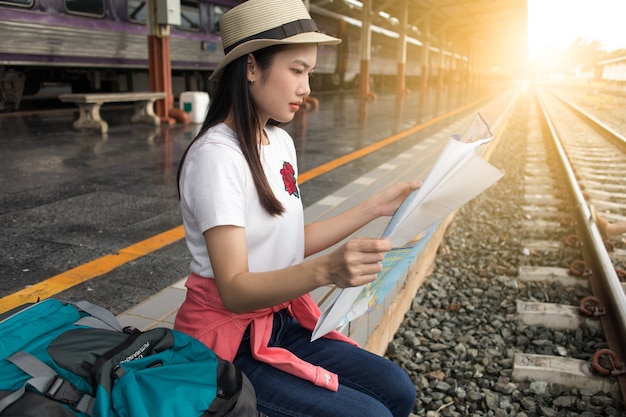 Photo femme assise et vue sur la carte à la gare en été