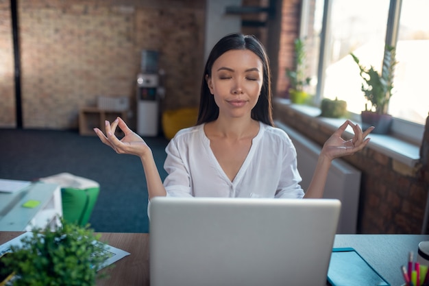 Femme assise avec les yeux fermés tout en étant d'une humeur paisible