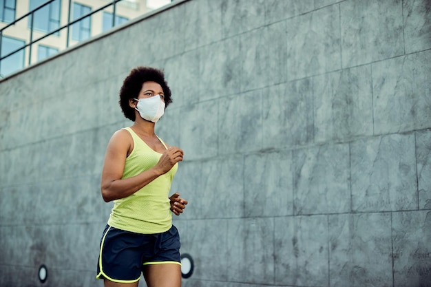 Femme athlétique afro-américaine faisant du jogging tout en portant un masque protecteur