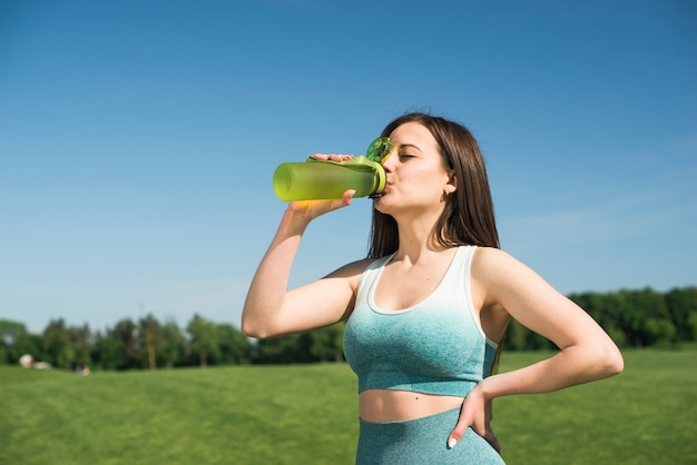 Femme athlétique buvant de l'eau isotonique