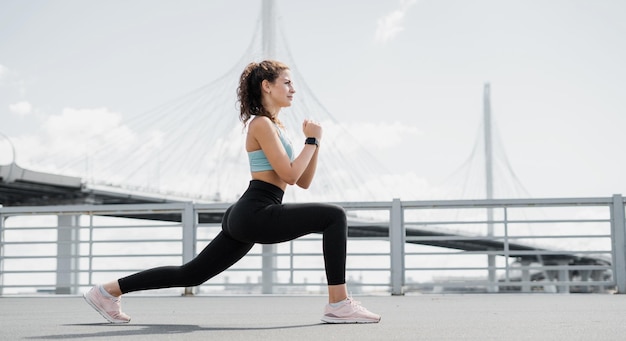 Une femme athlétique confiante fait des exercices de fitness dans la rue en baskets