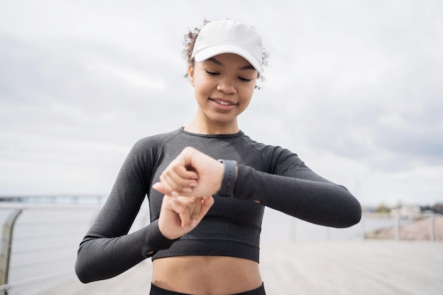 Une femme athlétique confiante utilise un tracker sur sa main une montre intelligente pour le sport