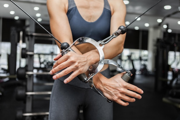 Femme athlétique exerçant des muscles dans une machine d'exercice à câble croisé dans une salle de sport moderne