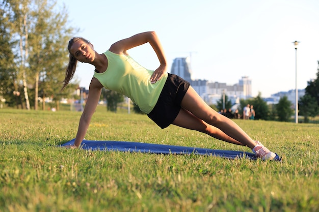 Femme athlétique faisant des exercices de planche en plein air. Élaborer le concept.