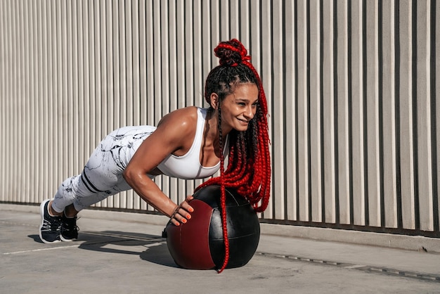 Femme athlétique faisant des pompes d'exercice avec med ball Force et motivationPhoto d'une femme sportive dans des vêtements de sport à la mode