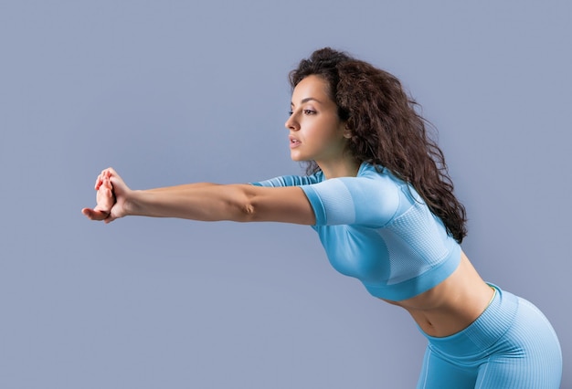 Femme athlétique faisant un studio d'exercice de flexion vers l'avant