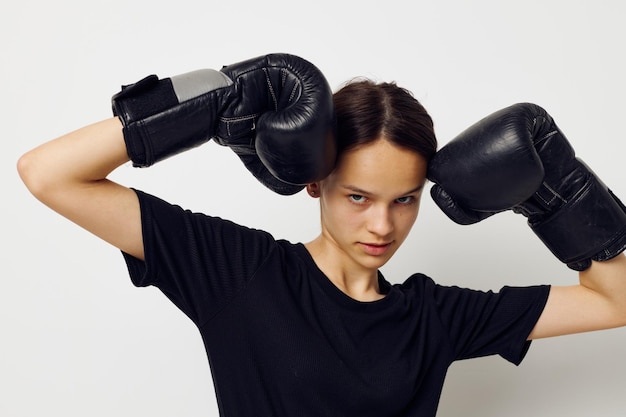 Femme athlétique en gants de boxe en pantalon noir et un entraînement de fitness tshirt