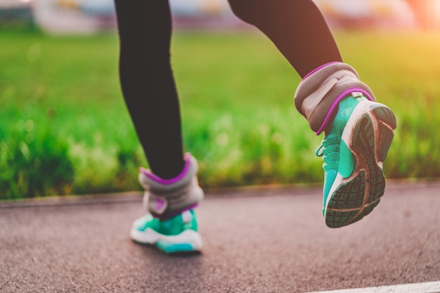 Femme athlétique marche avec des poids de sport pour renforcer les muscles et l'endurance pendant l'entraînement en plein air. Mode de vie sain et sportif.