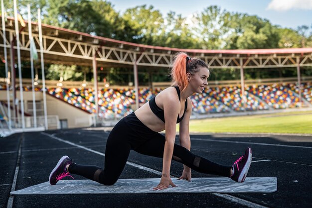 Femme athlétique pratiquant la pose de yoga sur le stade avec de l'herbe verte