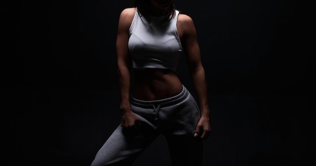 Femme athlétique de remise en forme posant en studio sur un fond sombre Photo d'une jolie femme en vêtements de sport à la mode Sports et mode de vie sain