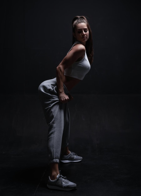 Femme athlétique de remise en forme posant en studio sur un fond sombre Photo d'une jolie femme en vêtements de sport à la mode Sports et mode de vie sain