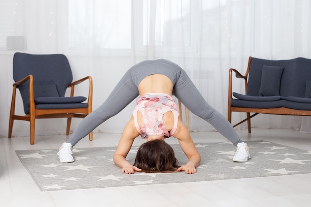 Femme athlétique avec ses jambes bien écartées se penche à l'envers