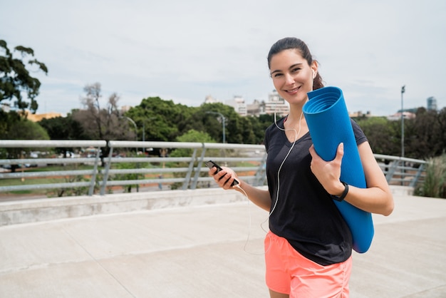 Femme athlétique tenant un tapis d'entraînement.