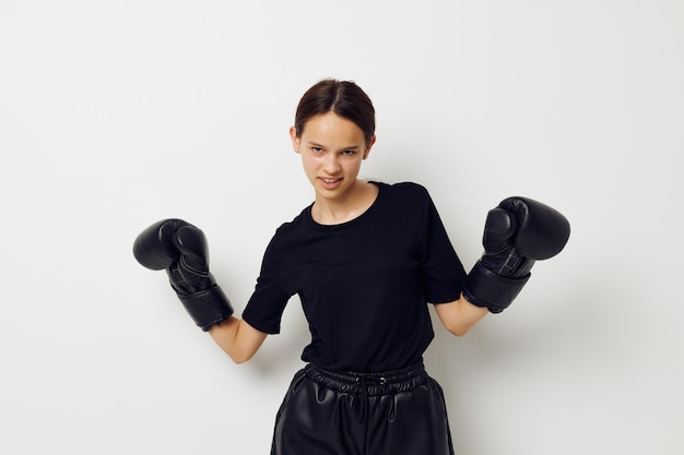 Femme athlétique en uniforme de sport noir gants de boxe posant fond isolé