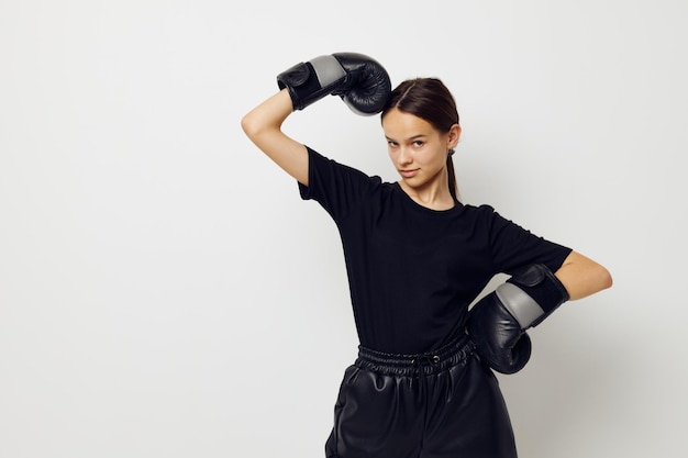 Femme athlétique en uniforme de sport noir gants de boxe posant fond isolé