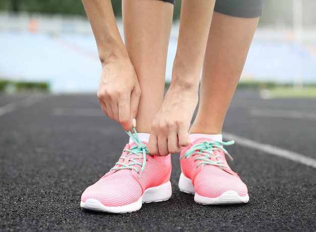 Femme attachant de la dentelle sur ses baskets sur un stade de course