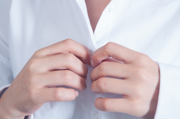 La femme attache le bouton de la chemise