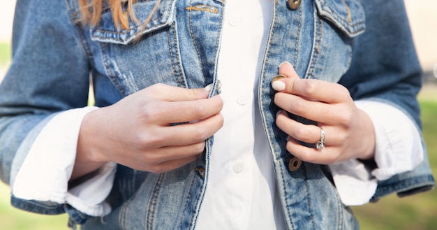 La femme attache des boutons une veste en jean.