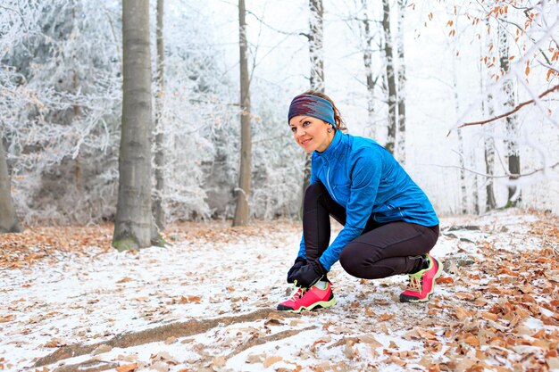 Photo une femme attache des lacets de chaussures dans la forêt pendant l'hiver.