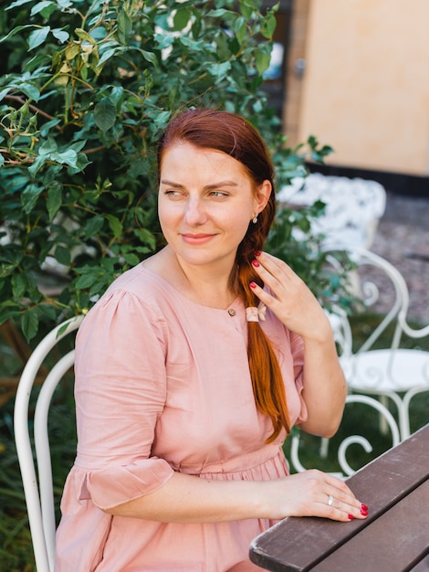 Une femme attend sa commande dans un café et s'assoit sur la terrasse. Rêver pendant une pause-café.