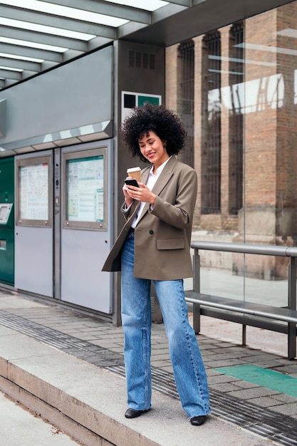 Femme attendant à l'arrêt de tram vérifiant son téléphone