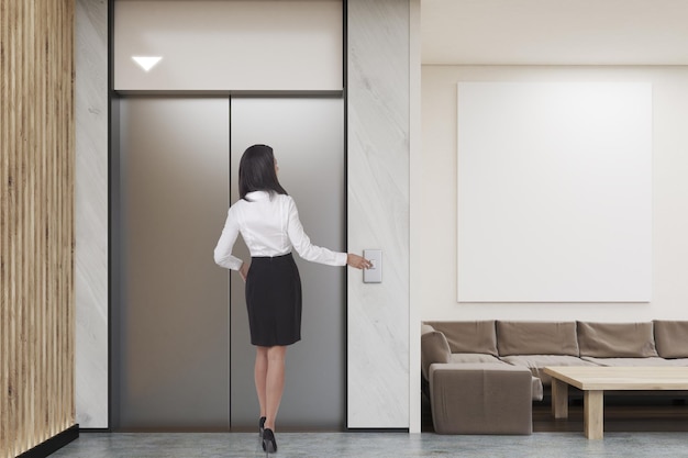 Femme attendant l'ascenseur dans le hall de l'entreprise