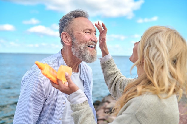 Femme attentionnée avec crème solaire et homme