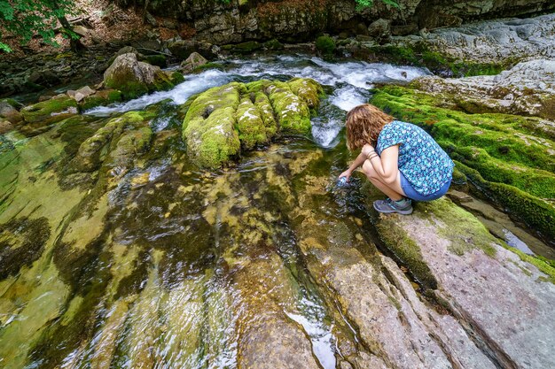 Femme attraper de l'eau d'une rivière d'eau propre dans les montagnes. Beauté et écologie dans un lieu sans pollution.