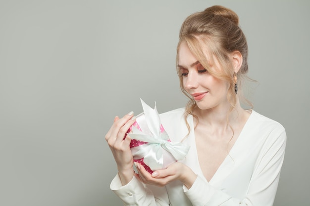 Une femme attrayante avec un cadeau sur un fond gris