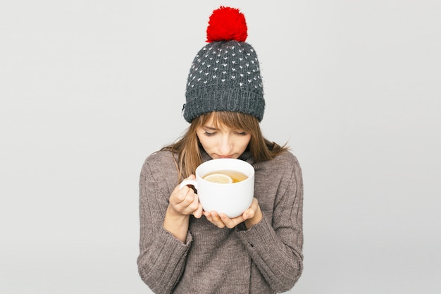 Femme au bonnet tricoté avec une tasse de thé