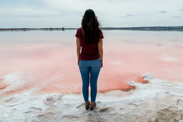 Femme au bord d'un lagon salé rose