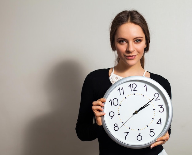 Femme au bureau avec une grande horloge blanche