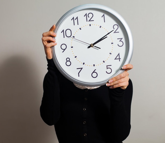 Femme au bureau avec une grande horloge blanche