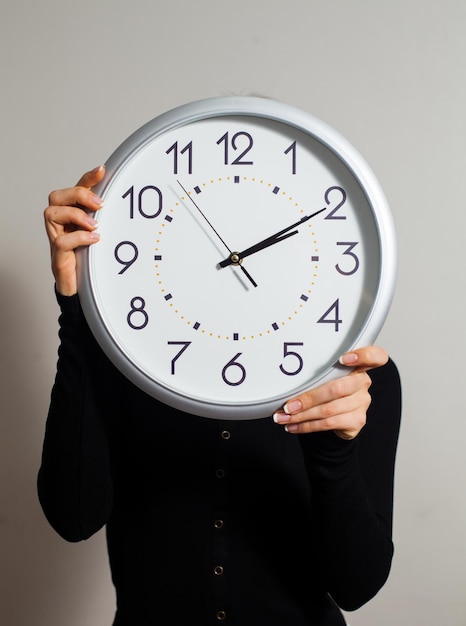 Femme au bureau avec une grande horloge blanche