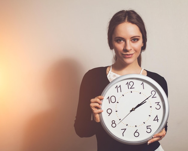 Femme au bureau avec une grande horloge blanche