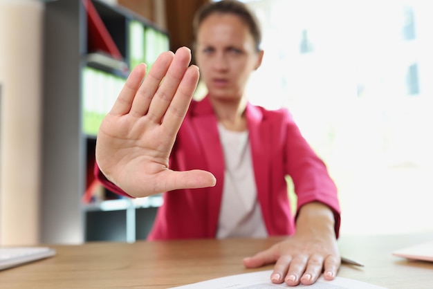 Une femme au bureau montre un geste de refus et de désapprobation