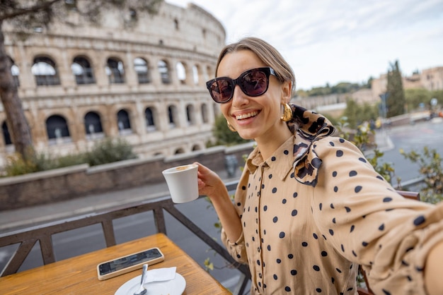 Femme au café en plein air devant le colisée à rome italie