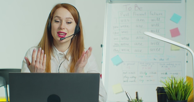 Femme au casque parlant aux étudiants par vidéoconférence à la classe vide.