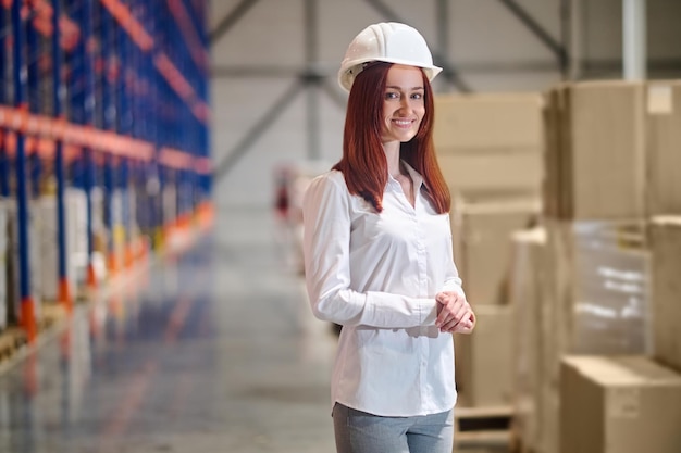 Femme au casque de sécurité debout dans l'entrepôt